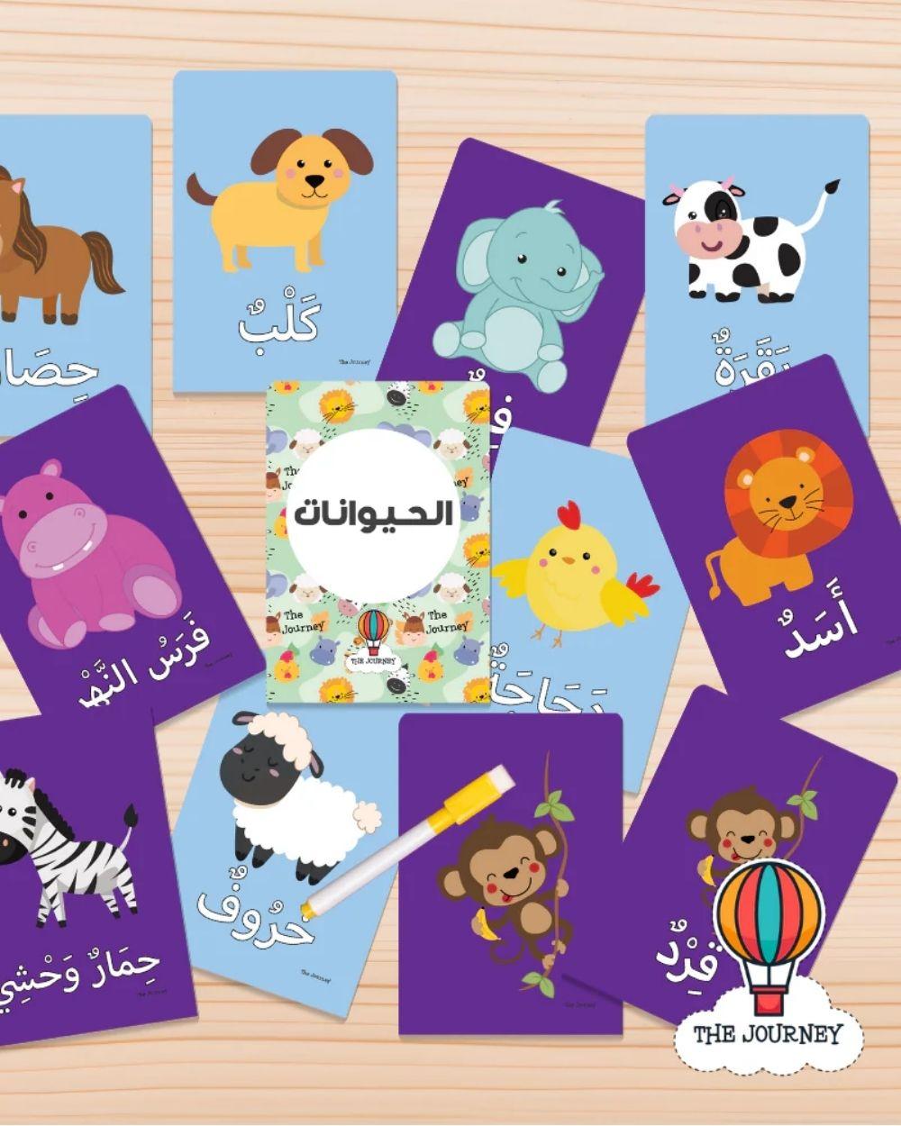 Educational cards with animal illustrations and Arabic text on a wooden surface