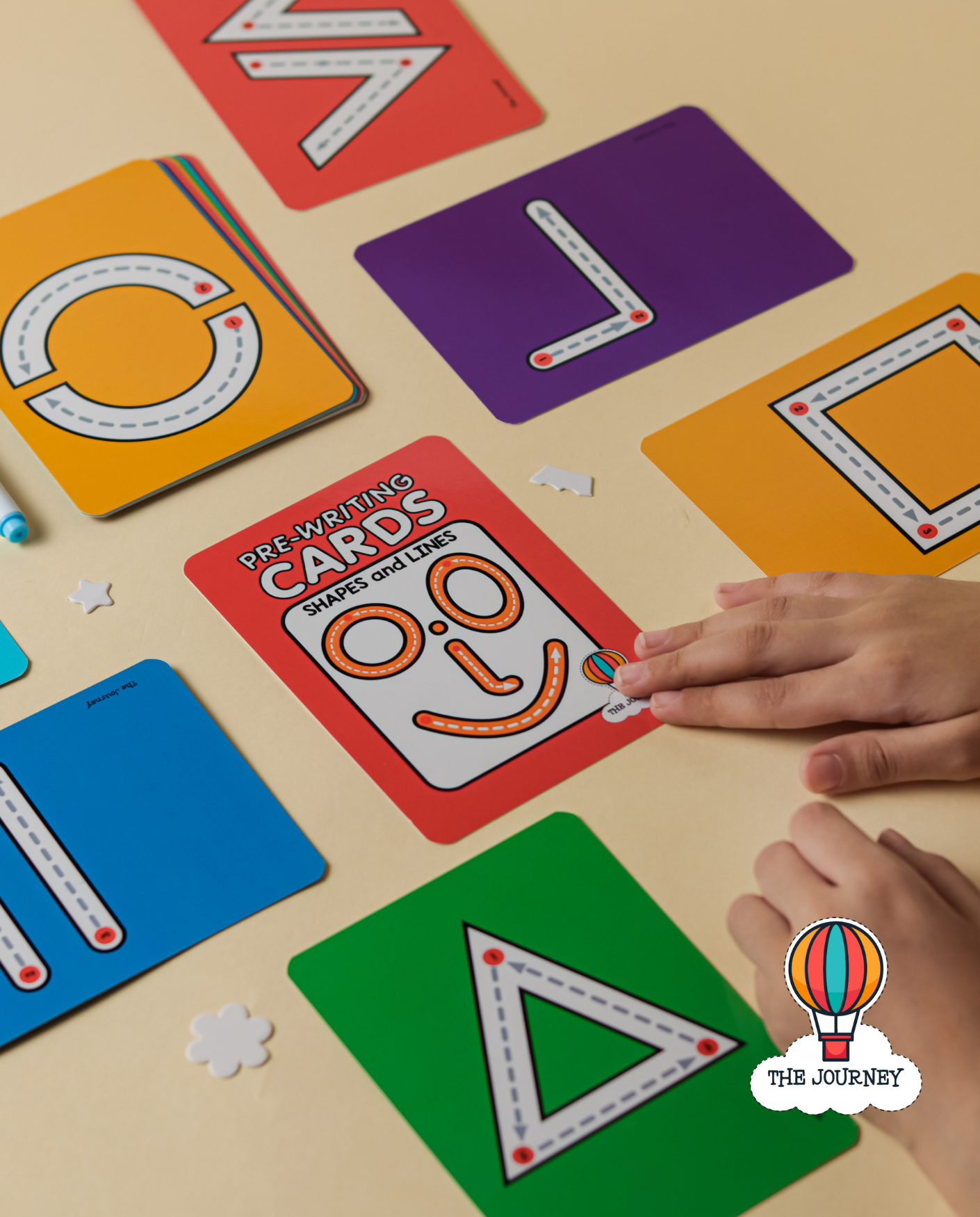 Hand of a child touching cover of pre-writing cards set on a laminated Ready to Write card with a whiteboard marker.